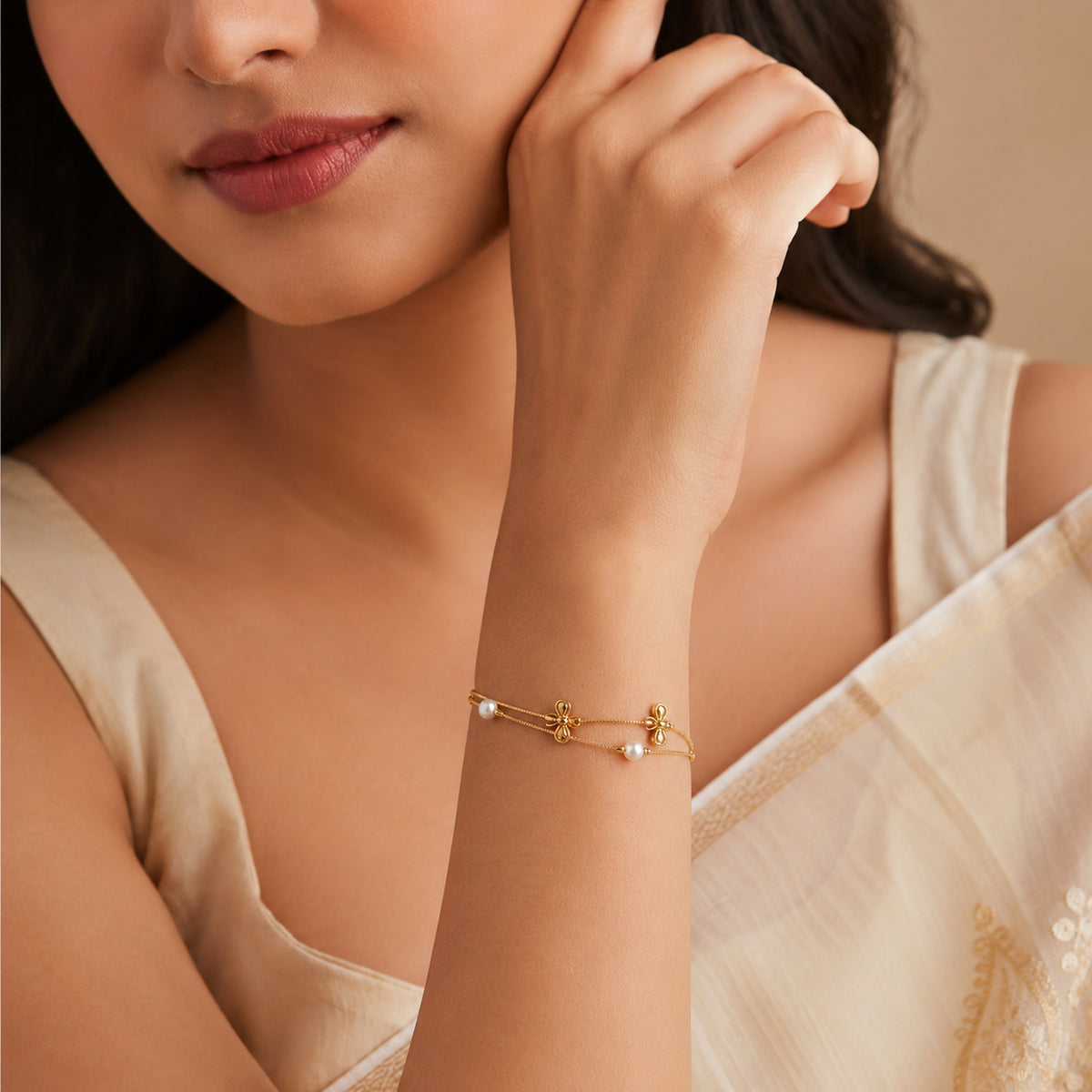 Bow and pearl-style bracelet worn with a cream saree