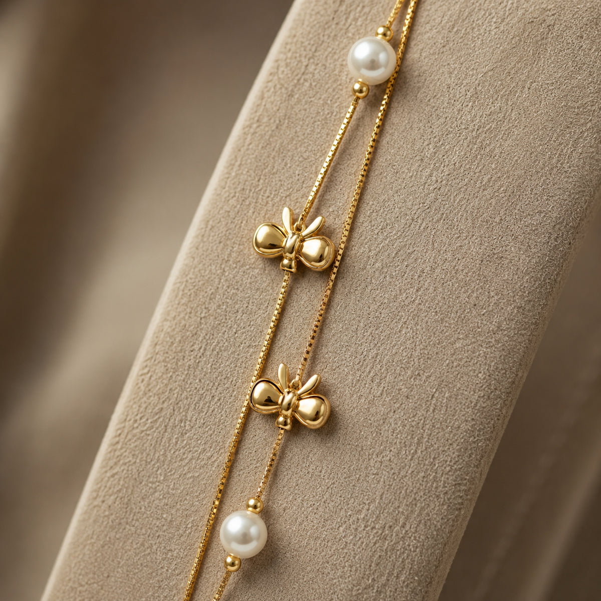 Close-up of the two polished bows and pearl-style beads on the double chain