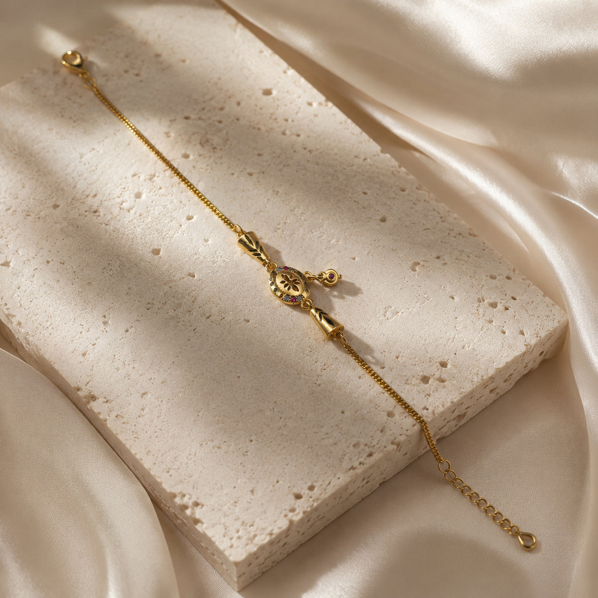 Floral charm bracelet arranged diagonally on a pale stone slab