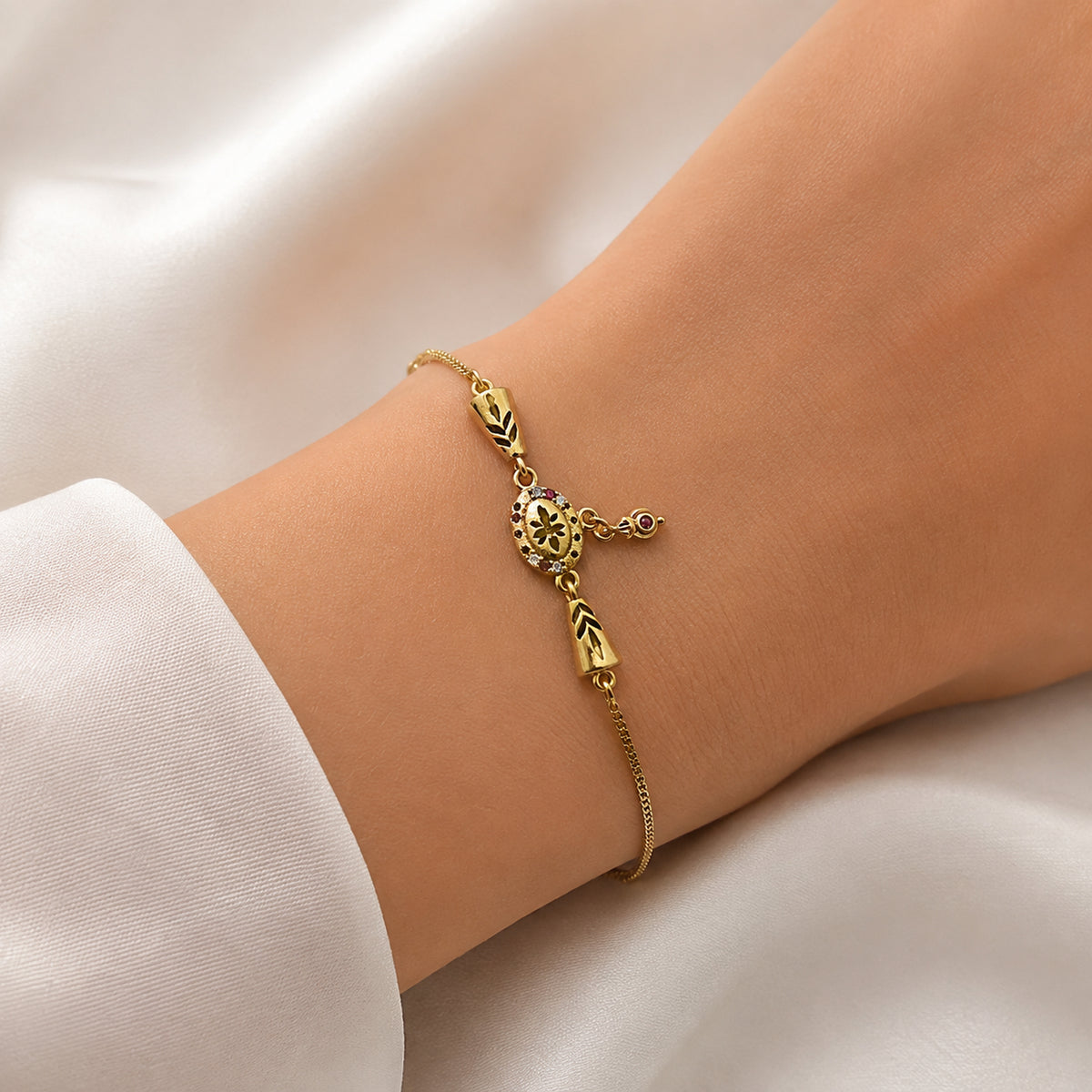 Gold-tone floral charm bracelet with tapered connectors on a wrist