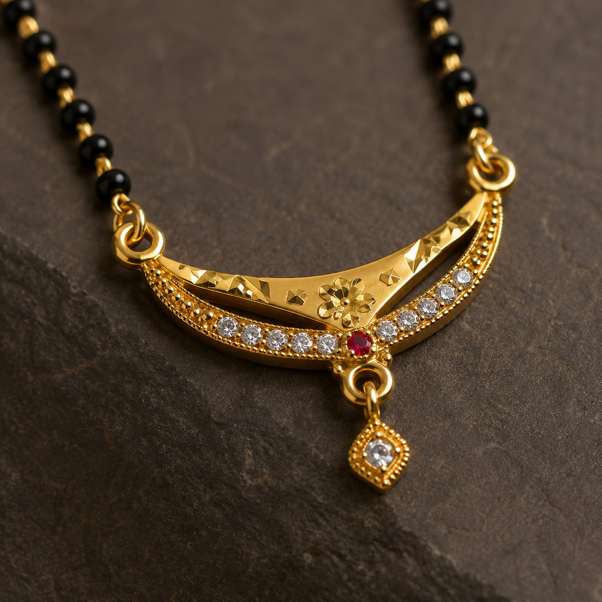 Close-up of the curved pendant, clear stones, red accent and hanging charm