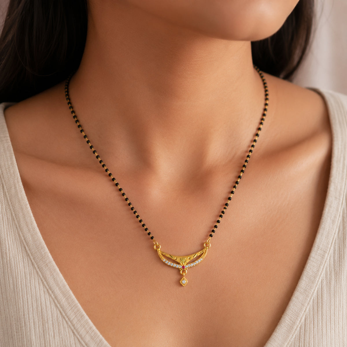 Close view of the black bead chain and curved pendant being worn
