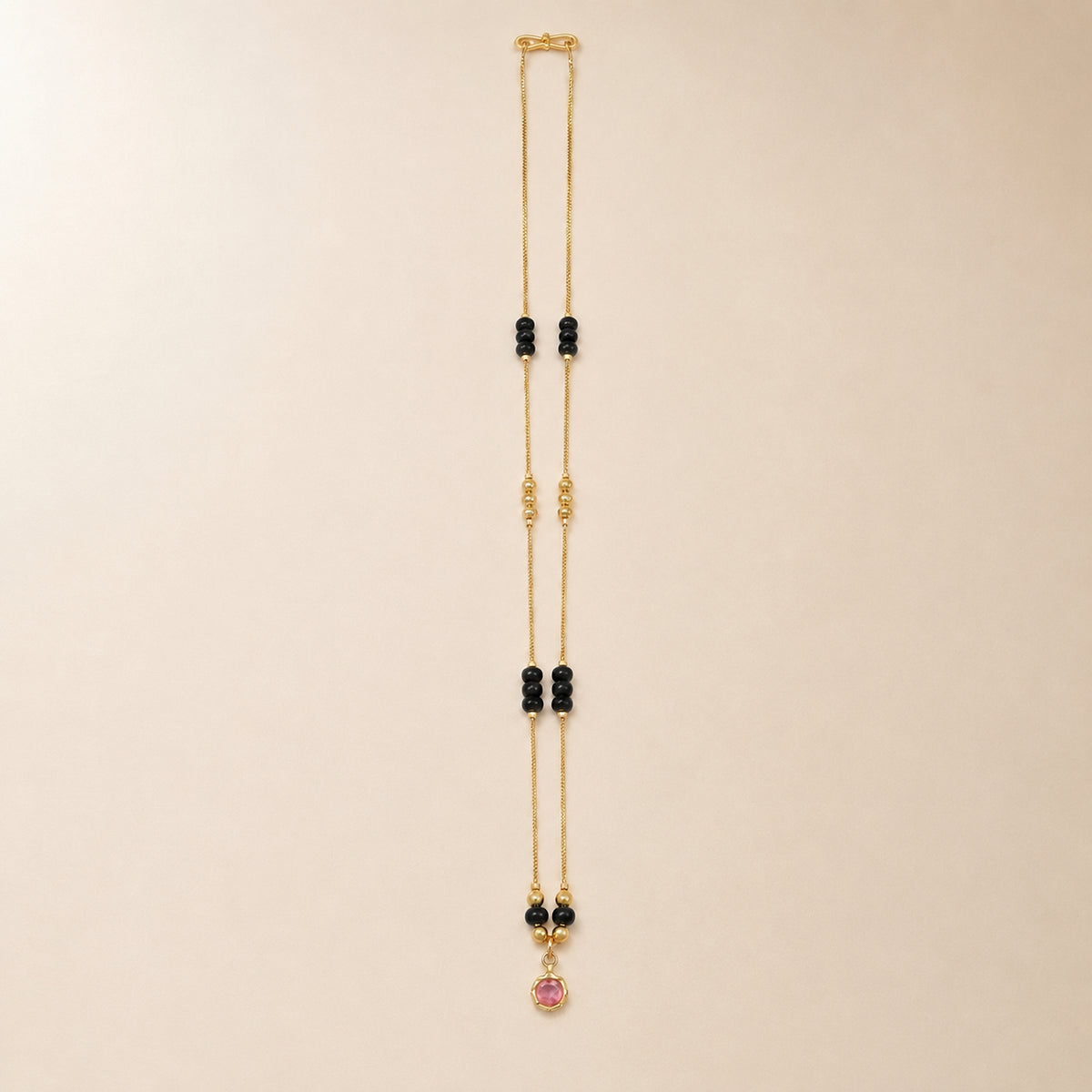 Black bead cluster mangalsutra with pink centre pendant on cream fabric