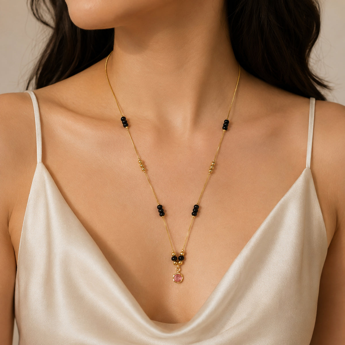 Close view of the spaced black bead clusters and pink pendant being worn