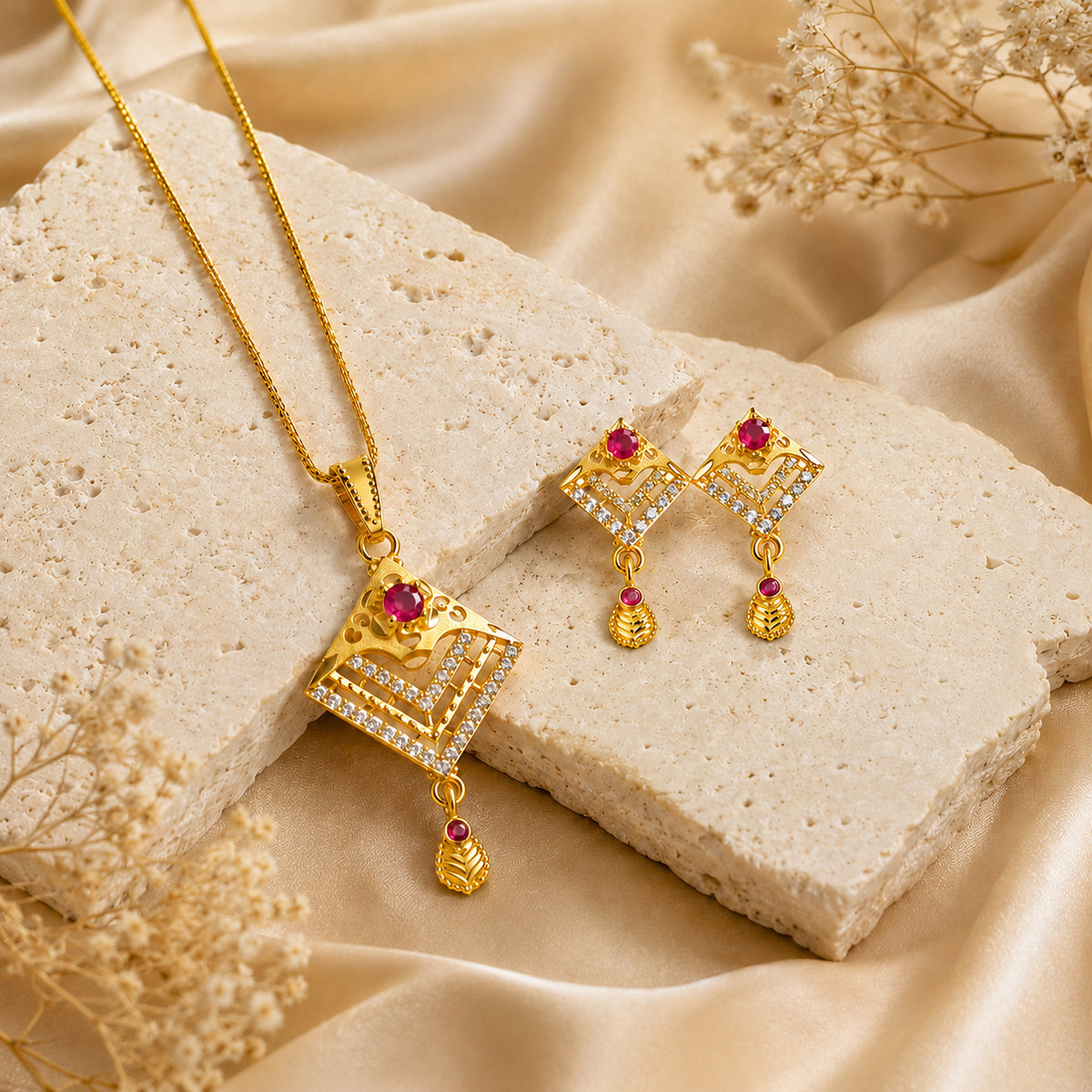 Gold-tone geometric pendant and earrings displayed on a pale stone slab