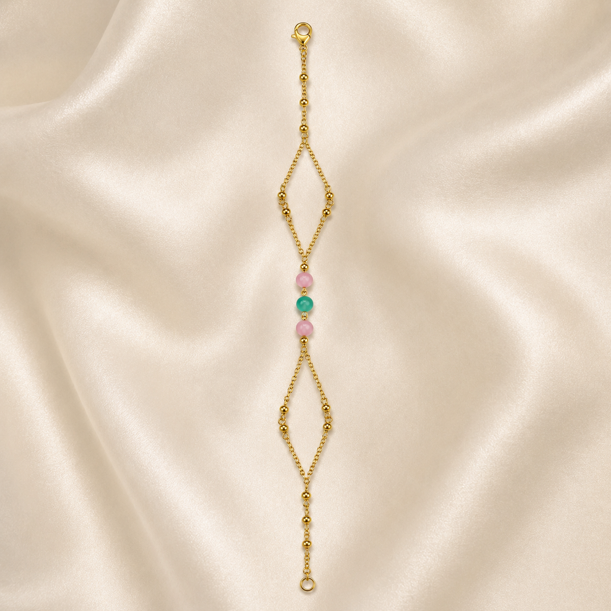 Pink and green bead bracelet with open diamond chains laid straight on ivory satin