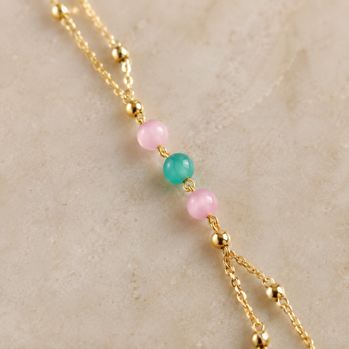 Close-up of the pink and green centre beads, gold-tone spacers and paired chains