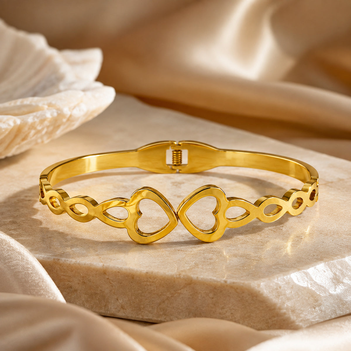 Gold-tone heart bangle displayed on a round pale stone base