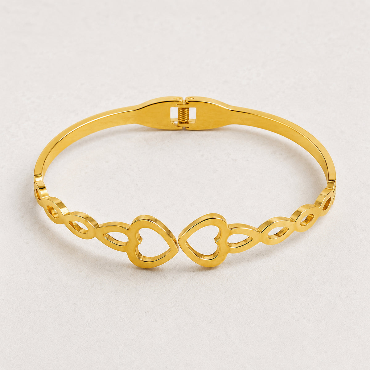 Double-heart bangle viewed from above on a pale background
