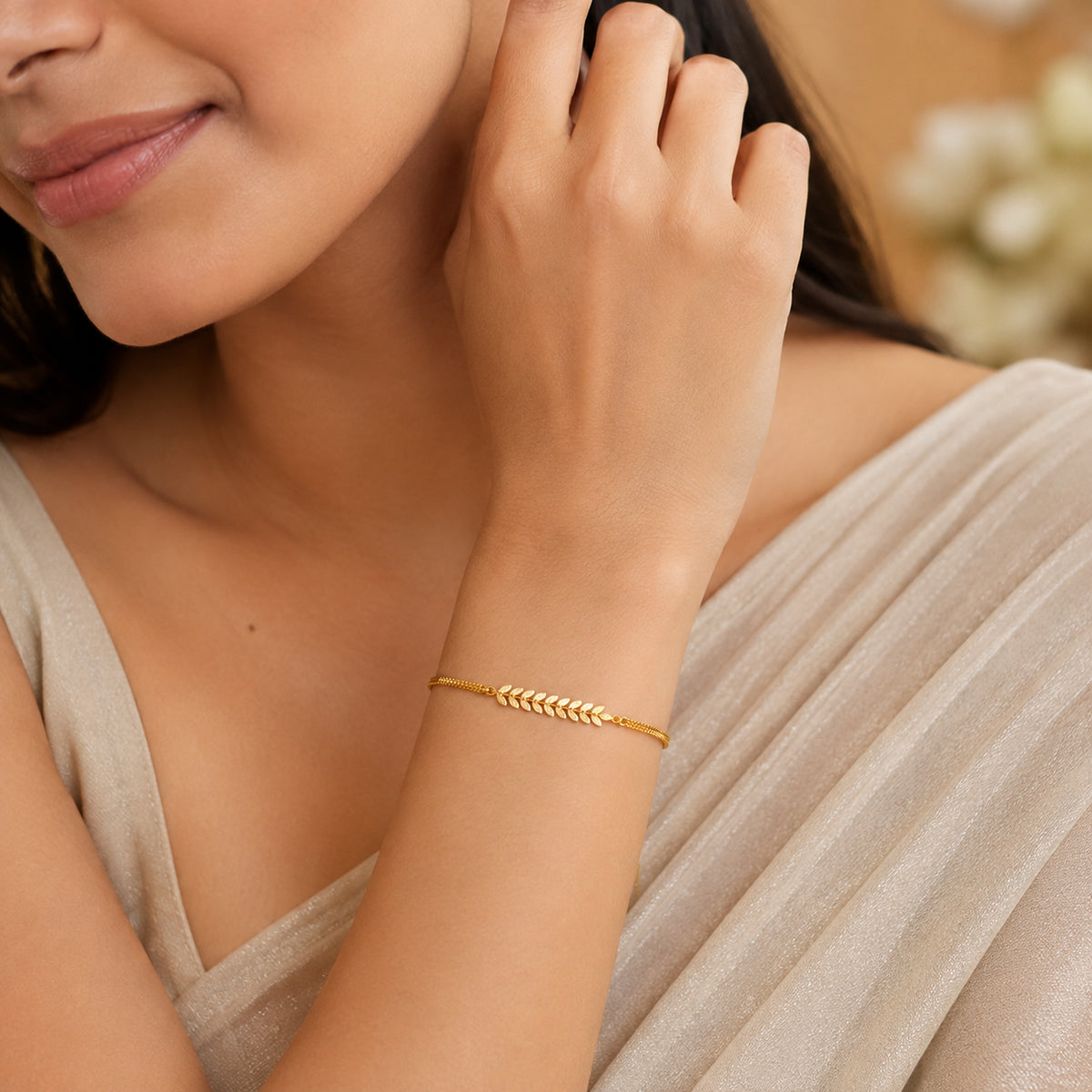 Gold-tone leaf bracelet worn with a cream saree