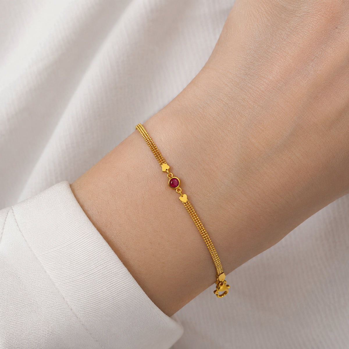 Gold-tone bracelet with a red-pink centre stone shown on a wrist