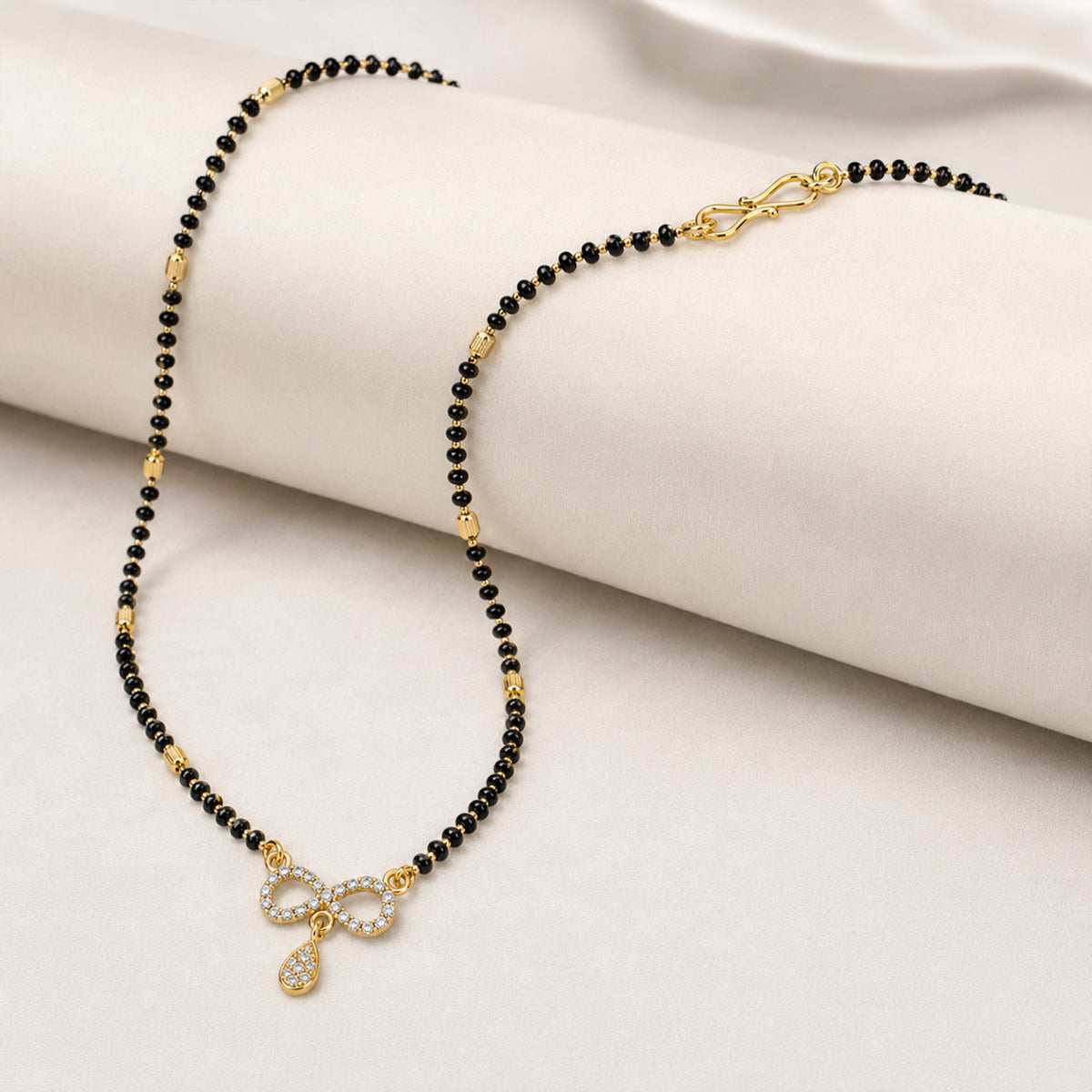 Black bead infinity-pendant mangalsutra draped over cream blocks
