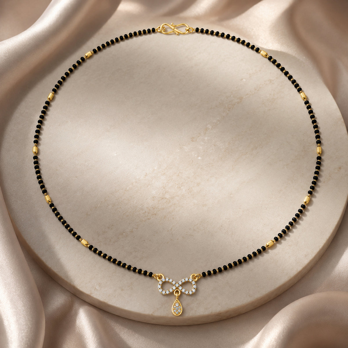 Infinity mangalsutra arranged around a cream display platform