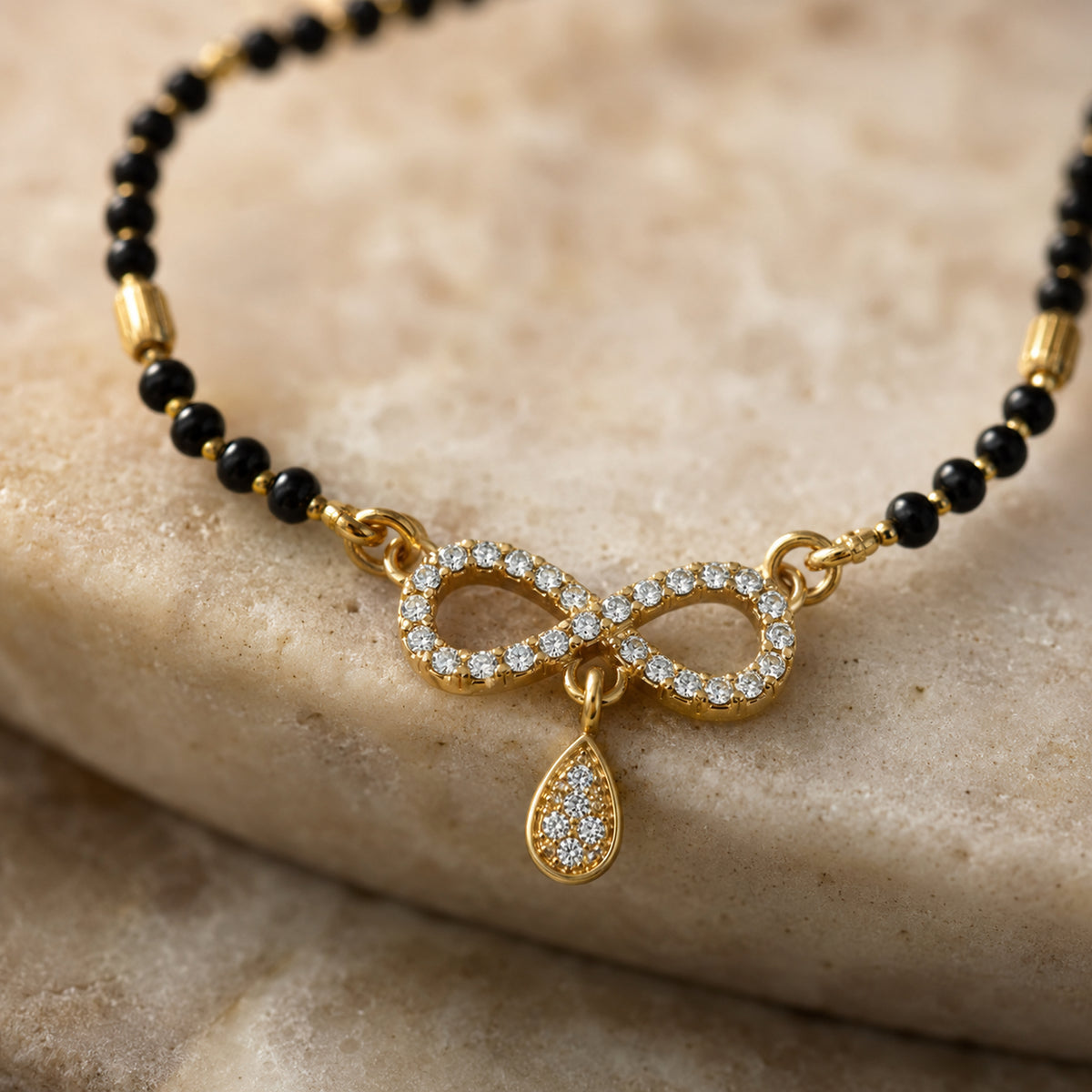 Close-up of the clear-stone infinity motif, teardrop drop and black beads