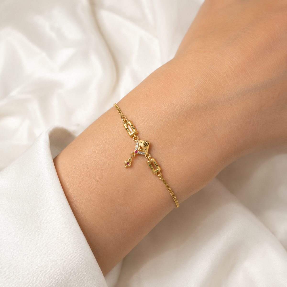 Geometric centre and hanging drop charm bracelet shown on a wrist