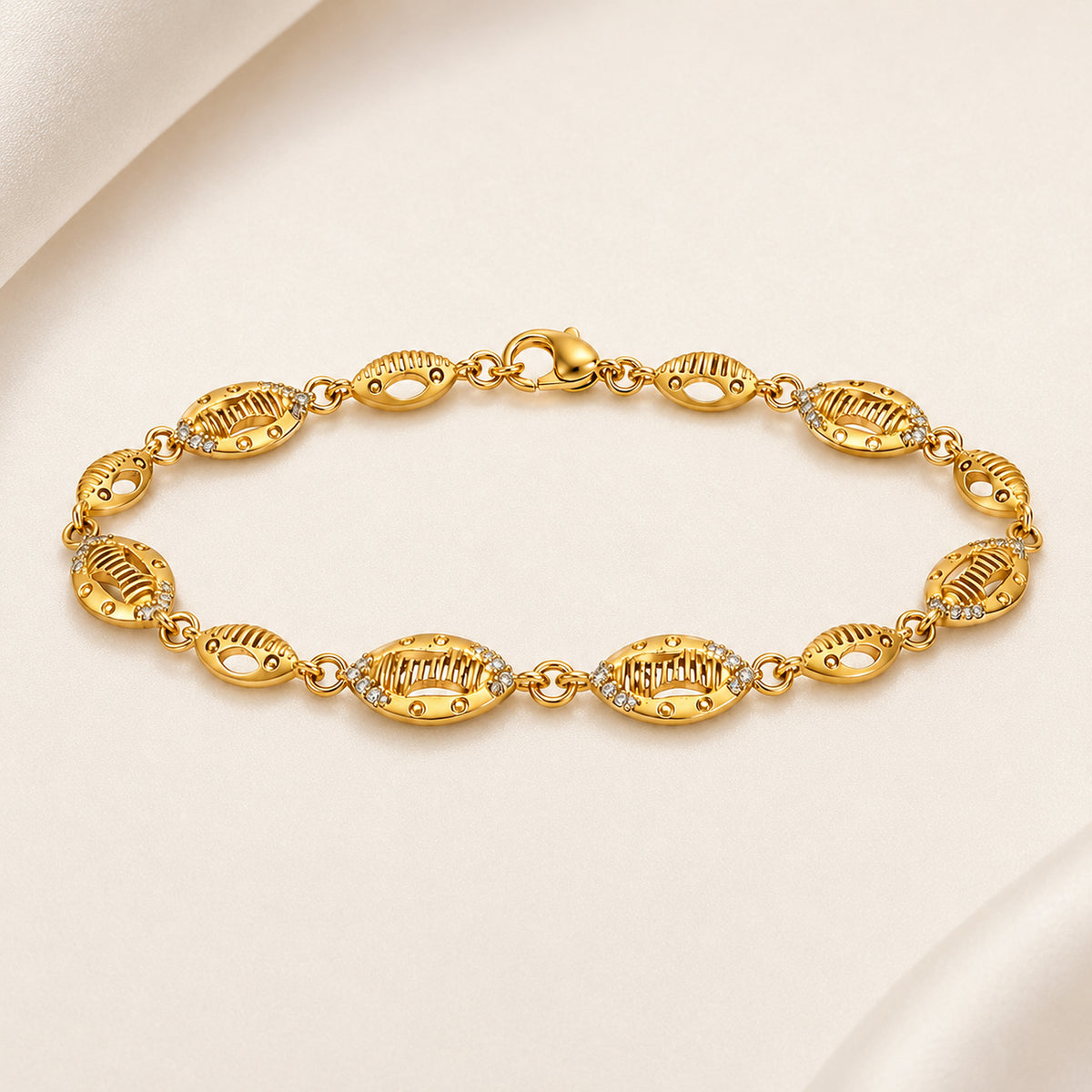 Textured oval link bracelet with clear stone accents on pale fabric