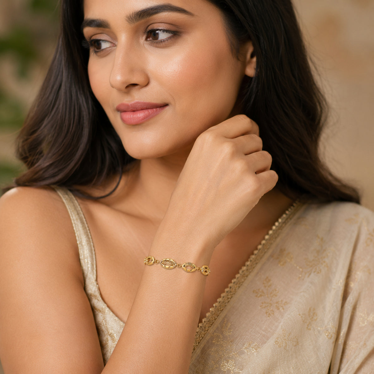 Gold-tone oval link bracelet worn with a cream saree