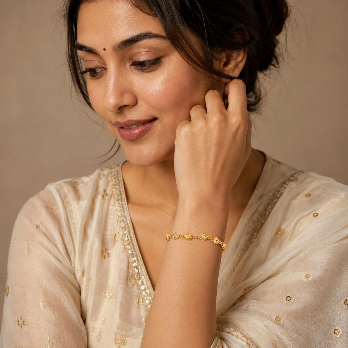 Gold-tone wave and bead bracelet worn with a cream embroidered outfit