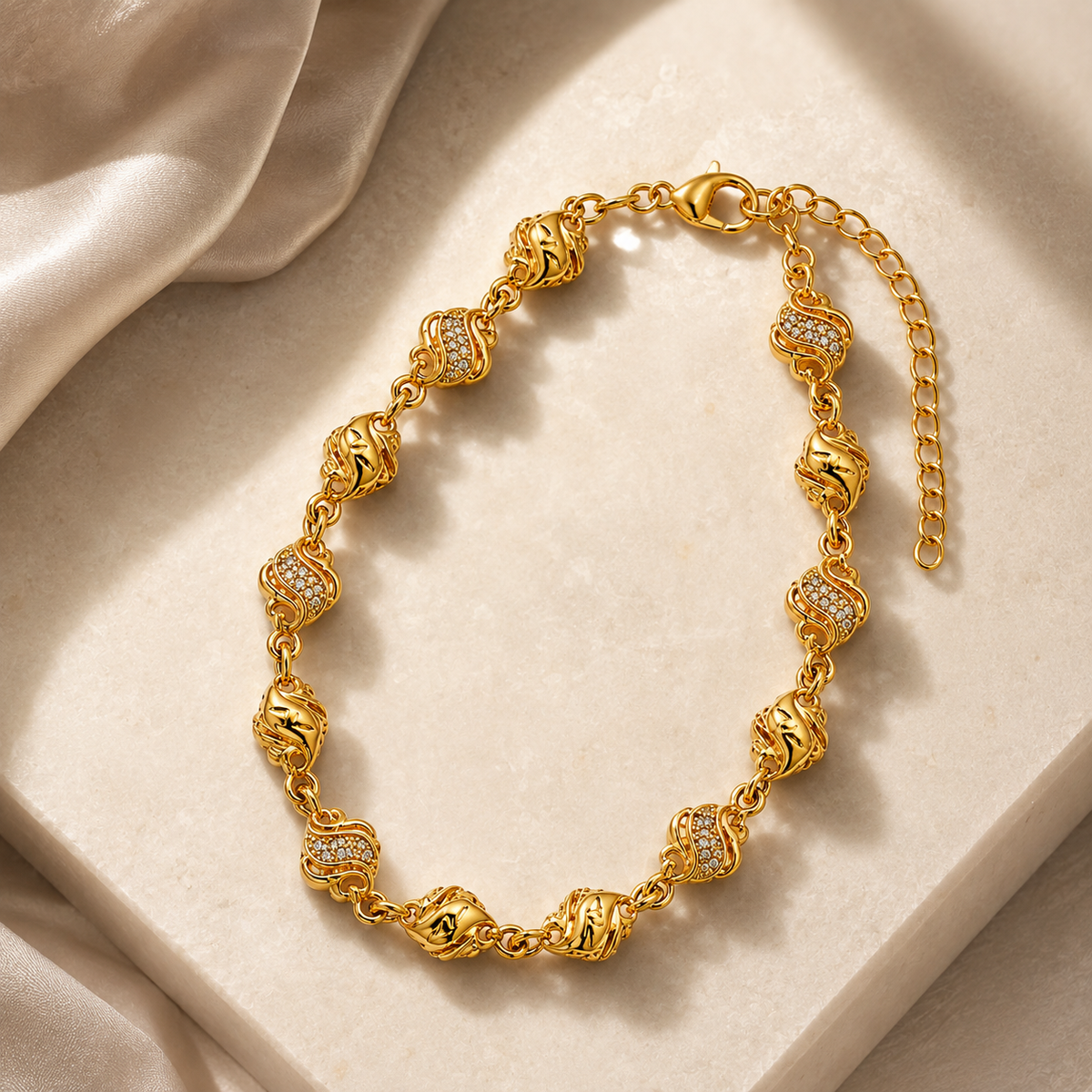 Wave and bead bracelet displayed on a pale stone slab beside satin