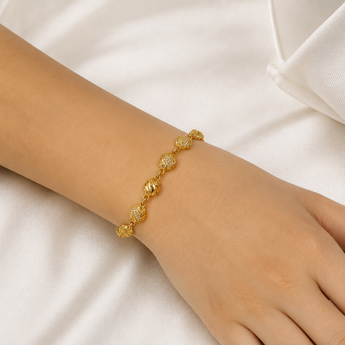Gold-tone wave and sculpted bead bracelet shown around a wrist