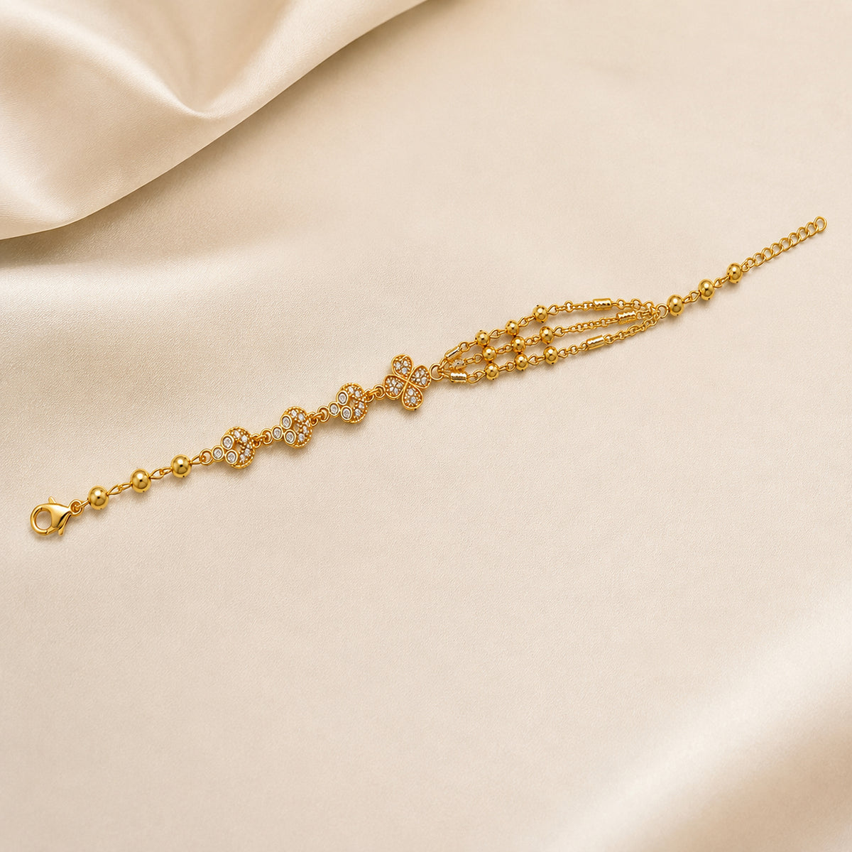 Floral bracelet with clear stone accents and layered chains on pale fabric