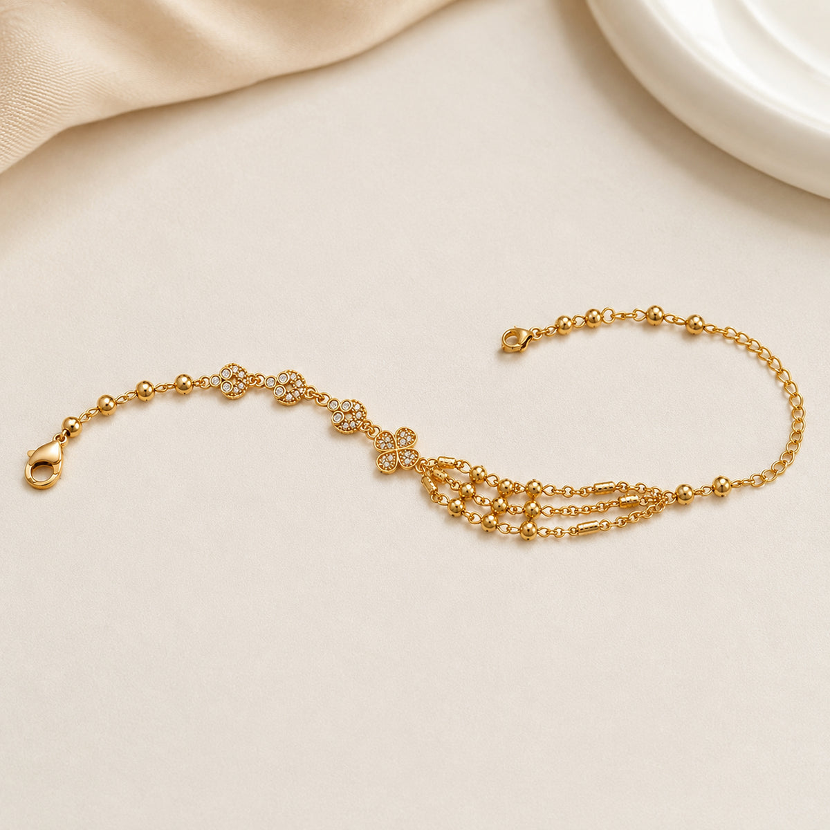 Floral multi-chain bracelet curved on pale fabric with the clasp visible