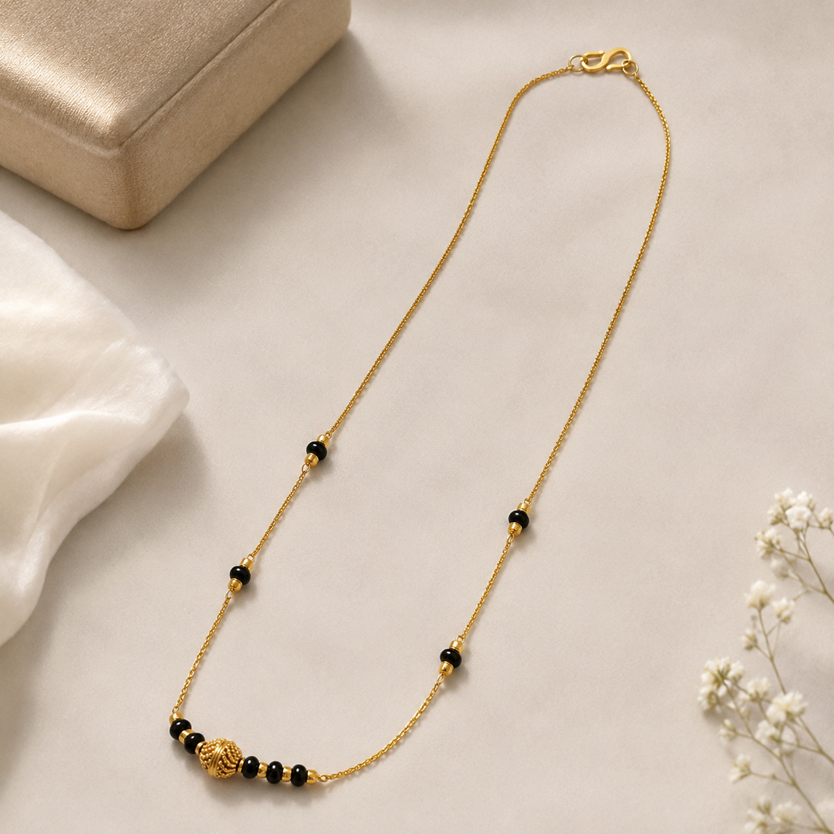 Textured-centre gold-tone mangalsutra arranged on folded cream fabric