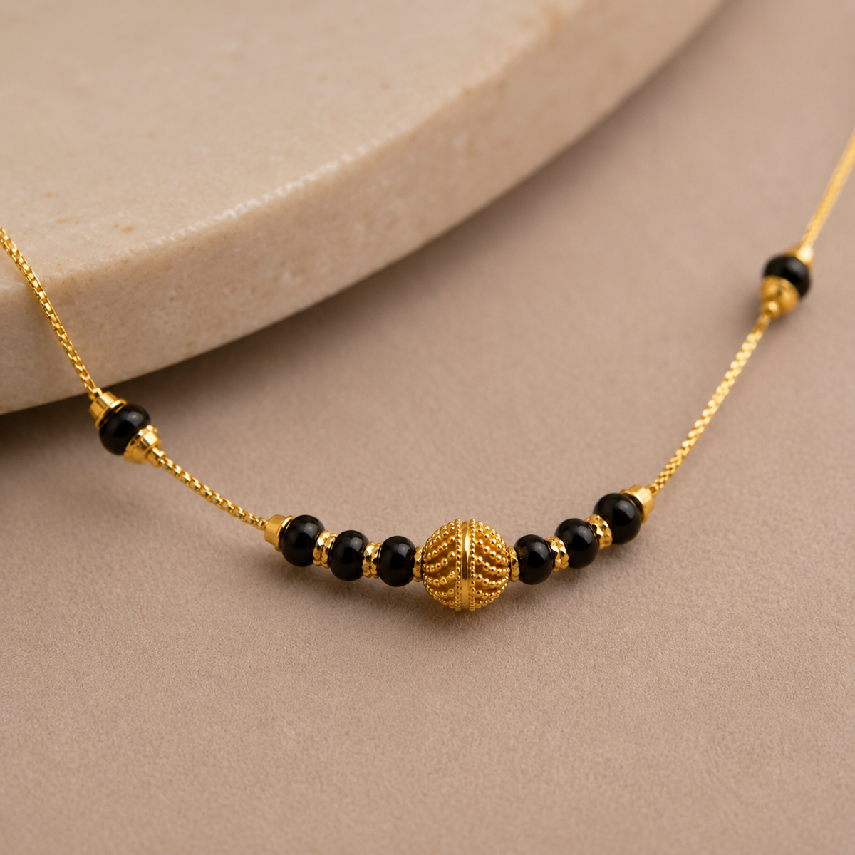 Close-up of the textured gold-tone centre bead between black bead accents