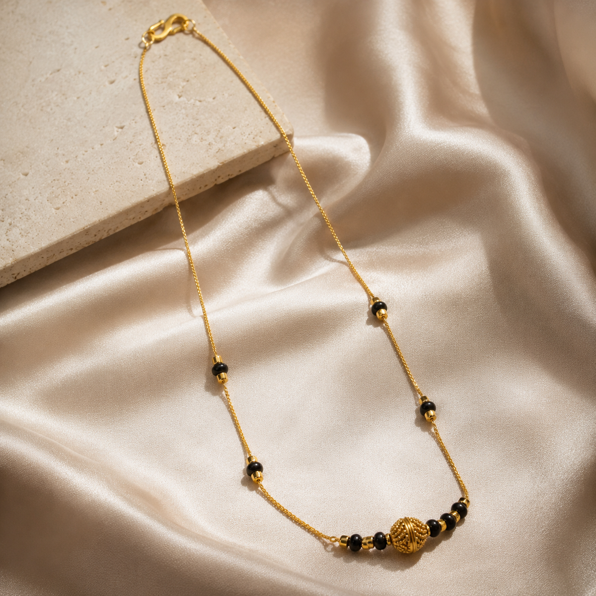 Black bead mangalsutra with textured centre draped over cream display blocks