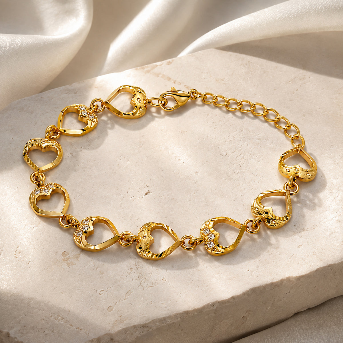 Gold-tone heart link bracelet displayed on a pale stone slab