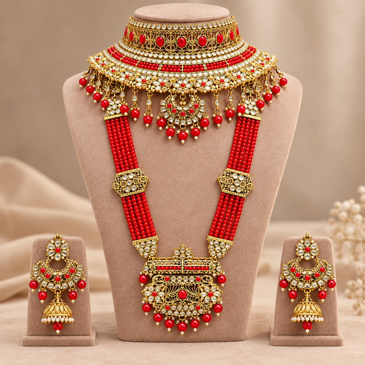 Red floral crescent choker and multi-strand beaded haar on a beige bust with earrings