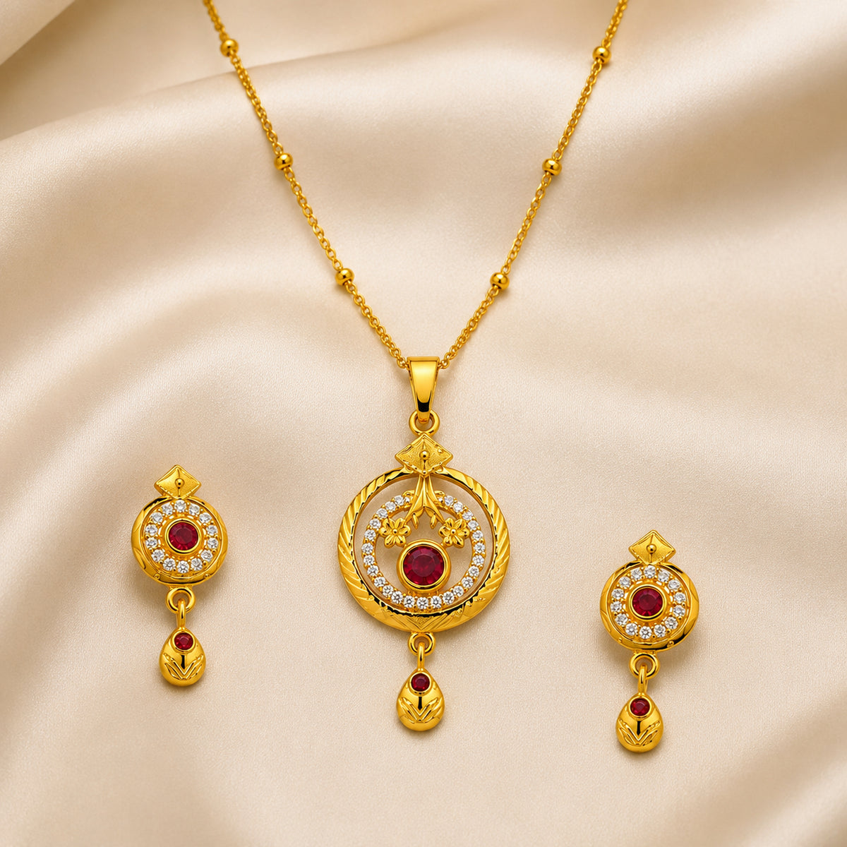 Ruby-red floral pendant and matching earrings arranged on cream fabric