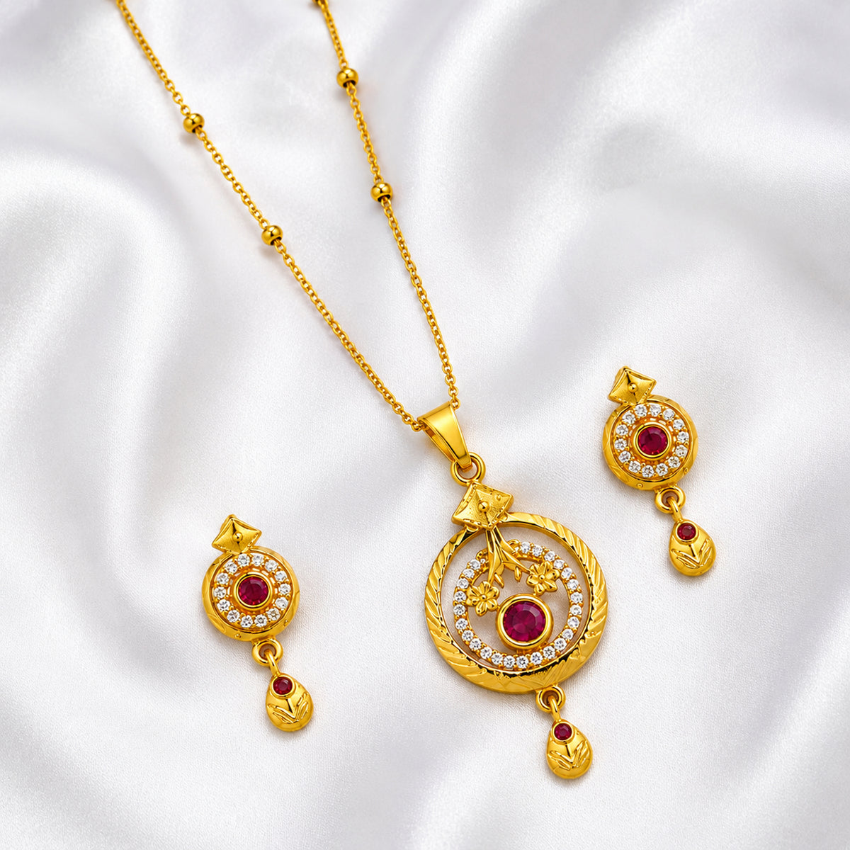 Gold-tone round pendant set with red and clear accents arranged on white fabric